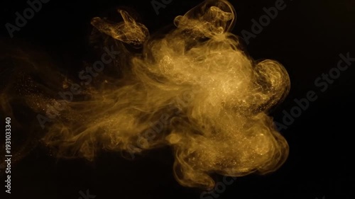 A shimmering golden cloud of liquid or particles emerges and swirls against a black background, gracefully expanding into an intricate, mesmerizing abstract form.