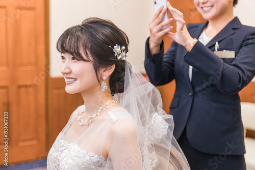 Canvas-taulu A planner woman taking photos with a smartphone of a bride and groom in a weddin