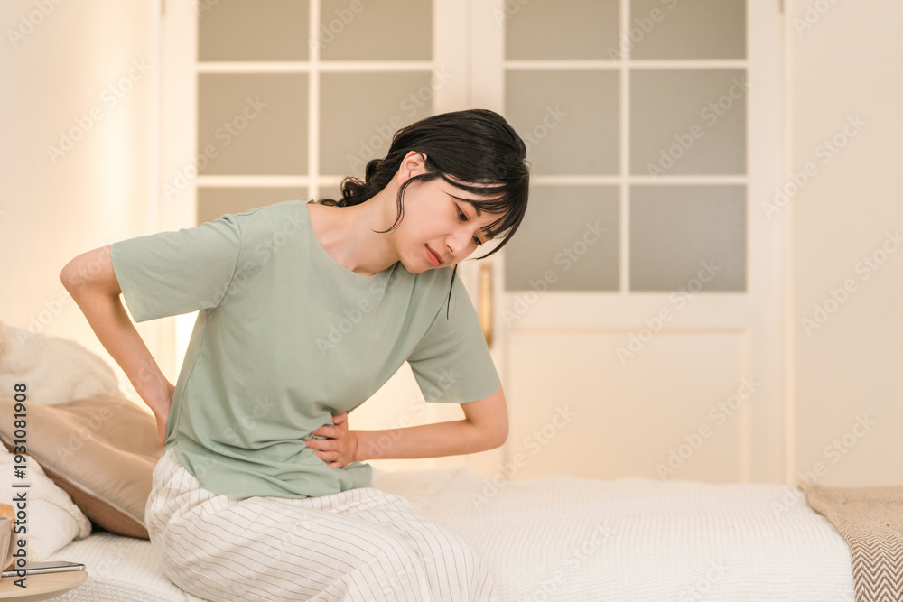 Behang Young Asian woman suffering from abdominal pain and menstrual cramps in her bedr