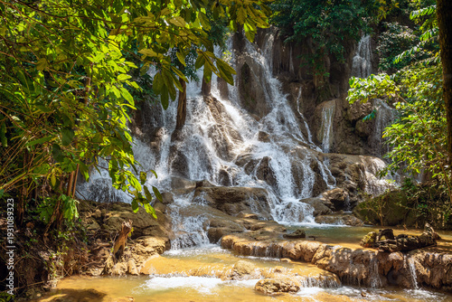 Serene tropical Dai Chong Thong waterfall cascade over limestone rock in lush forest at Sangkhlaburi, Kanchanaburi, Thailand under soft morning light