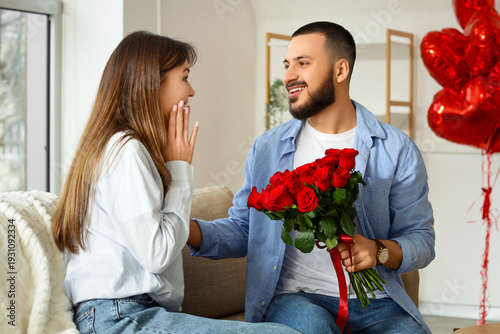 Young man giving bouquet of...