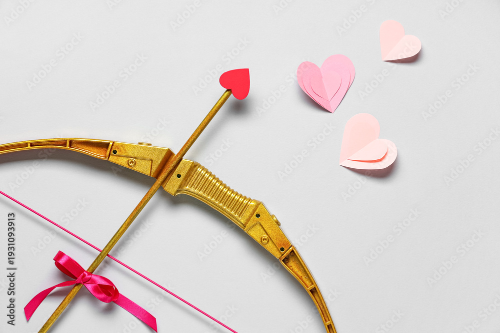 Naklejka premium Composition with cupid's bow and paper hearts on grey background. Valentine's Day celebration