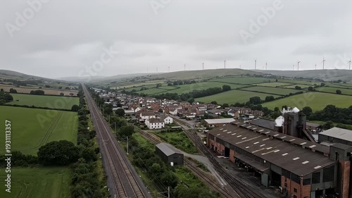 Aerial view of a rural village with railway lines and industrial buildings.