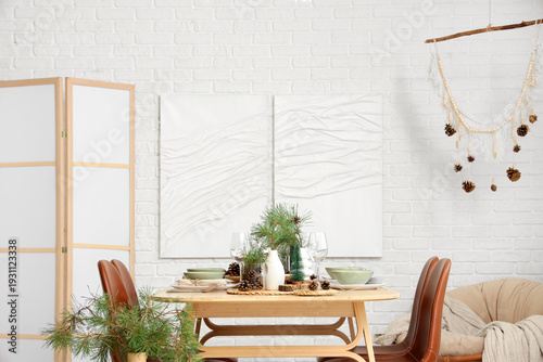 Interior of room with dining table, fir branches and paintings