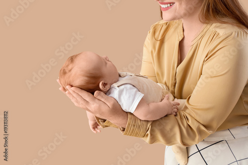 Cuadro en lienzo Beautiful young happy mother with her cute sleeping little baby on beige backgro