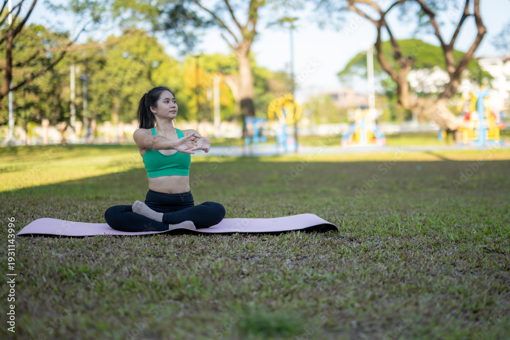 Fototapeta premium Woman practicing yoga stretching outdoors in park