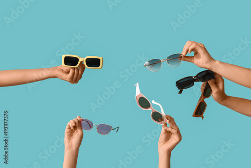 Foto Female hands with many stylish sunglasses on blue background