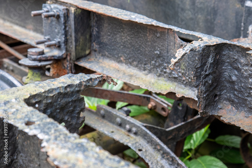 Oxidized structural metal revealing material fatigue. Weathered chassis fragment with peeling surface layer. Industrial decay texture on aged transport component. 