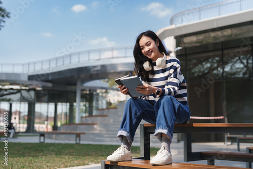 Young student woman enjoying campus life, reading and smiling