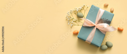 Easter eggs with gypsophila flowers and gift box on beige background