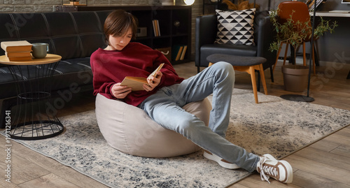 Teenage boy reading book at...