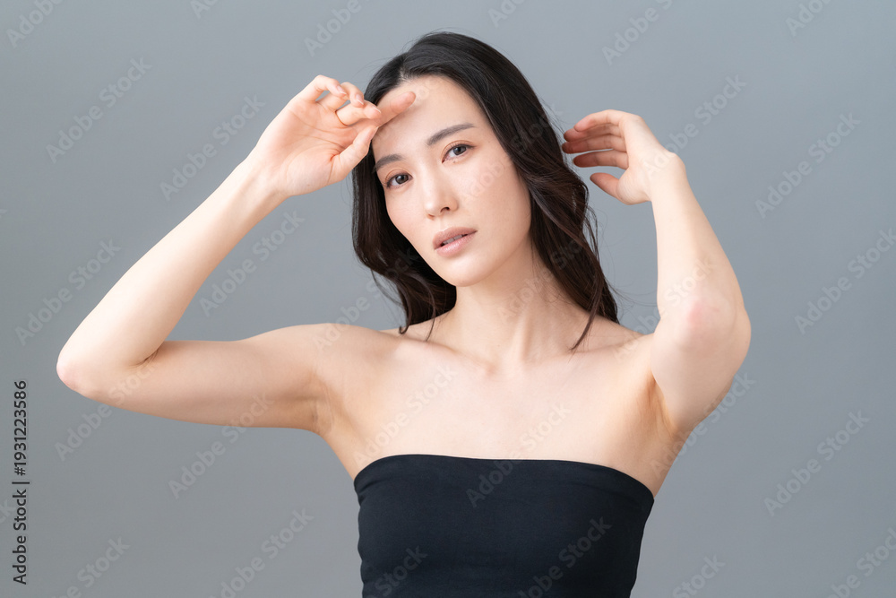 Fototapeta premium グレー背景でスキンケアをする女性のビューティーイメージ