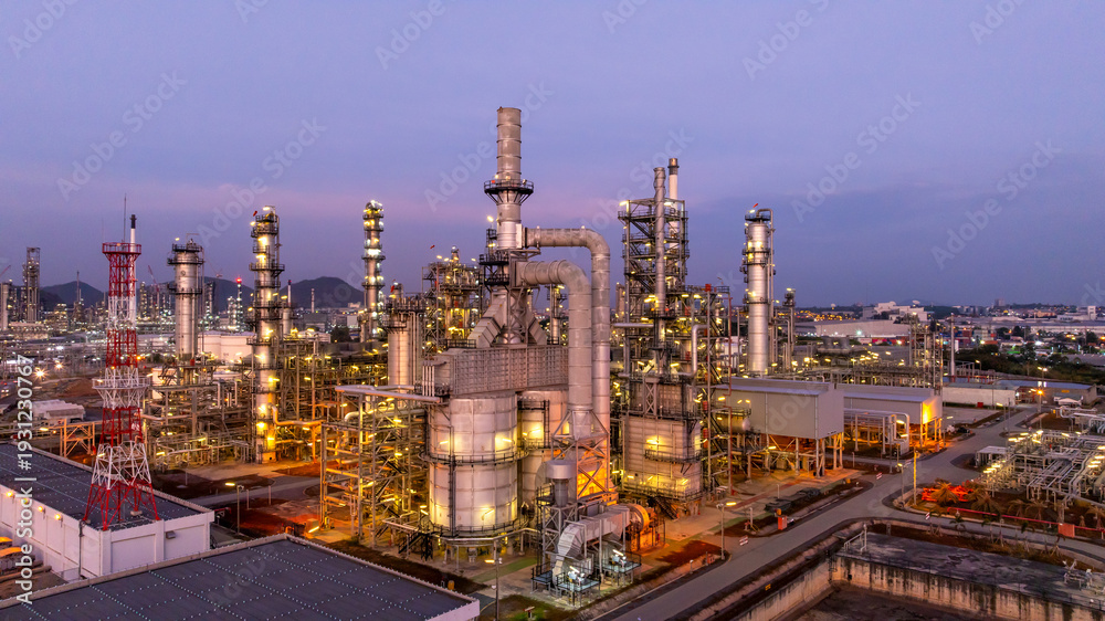 Fototapeta premium Aerial view oil and gas industrial refinery at twilight, Oil refinery and Petrochemical plant pipeline steel, Refinery factory oil storage tank and pipeline steel at night.