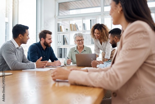 Diverse business team collaborating around a table with a laptop in a modern corporate office