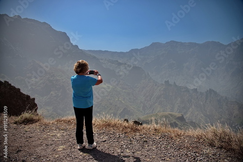 Rear view of senior woman taking photo in the volcanic landscape
