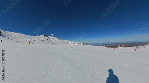 4K First-person POV skiing at Sierra Nevada Resort, Spain, descending a wide groomed run under a clear blue sky and intense winter sun