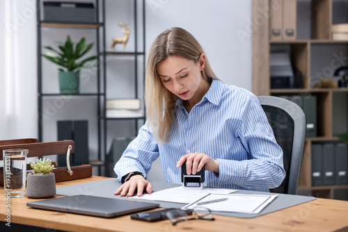 Fotografia Notary stamping document at wooden desk in office