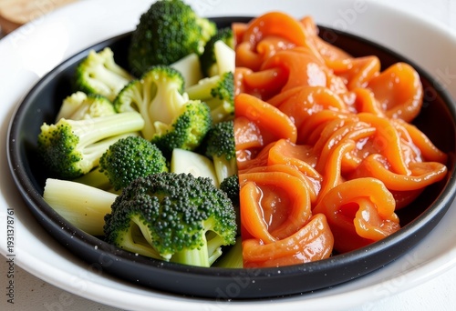 A visually contrasting culinary presentation of vibrant green broccoli florets paired alongside glazed orange seafood delicacy on a divided round black plate