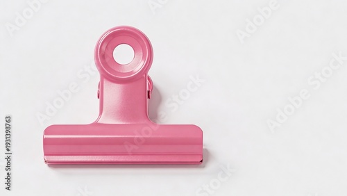 features a single, pink metal binder clip centered against a plain white background. The clip has a smooth, glossy finish and a circular hole at the top, which is typical for hanging or attaching purp