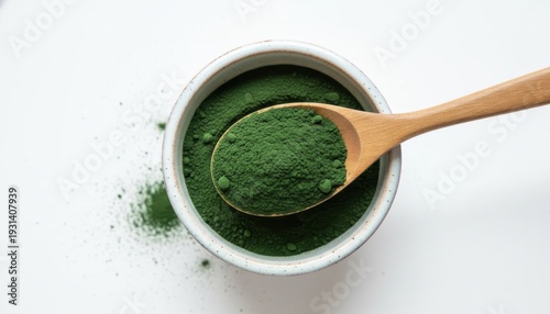 Vibrant green powder scooped from a bowl with a wooden spoon, illustrating a healthy superfood ingredient.