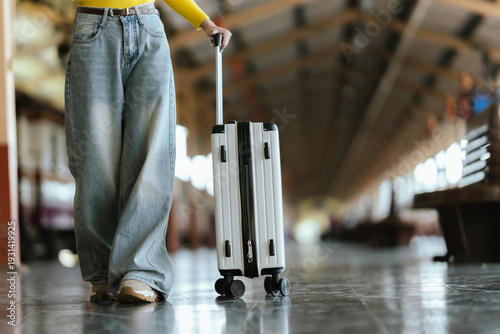 Stylish young woman traveling at train station with suitcase, traveling alone on vacation or business trip, enjoying summer city adventure.	