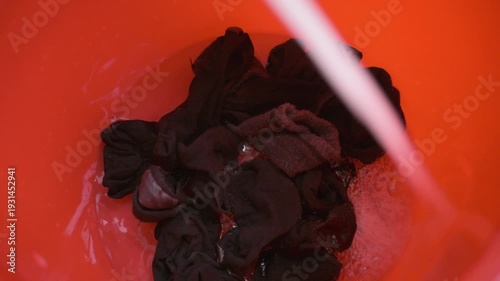 adding water and detergent to the bucket with socks, creating lots of bubbles