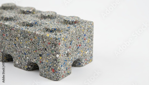 Wallpaper Mural A close-up view of a grey concrete Lego brick with multicolored speckles, showcasing its textured surface and modular design on a plain surface. Torontodigital.ca