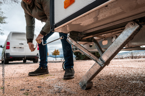 Fotografie Man adjusting the leveling legs of his caravan trailer with a manual crank