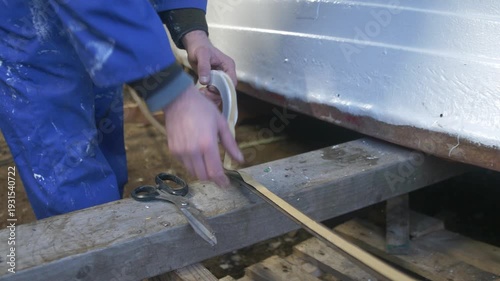 Applying butyl rubber tape to steel keel band for boat repair