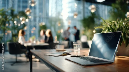 Wallpaper Mural Modern Office Workspace: An open laptop sits on a sleek wooden desk, beside a glass of water and a cup of coffee, set in a modern office space, hinting at the bustling work environment beyond. Torontodigital.ca