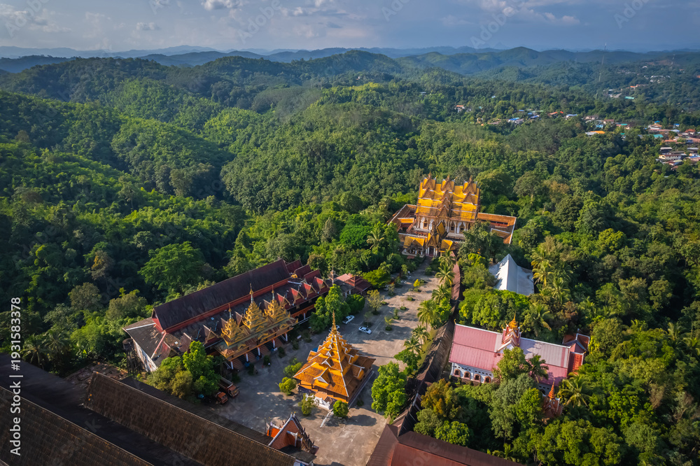 Obraz premium Aerial view of Wat Wang Wiwekaram temple surrounded by lush green forest and scenic lake in Sangkhlaburi, Kanchanaburi, Thailand during golden hour