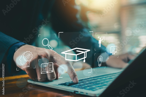 Foto Online education concept with businessman using laptop and touching virtual graduation cap icon, e learning platform, digital training, knowledge management and smart technology interface