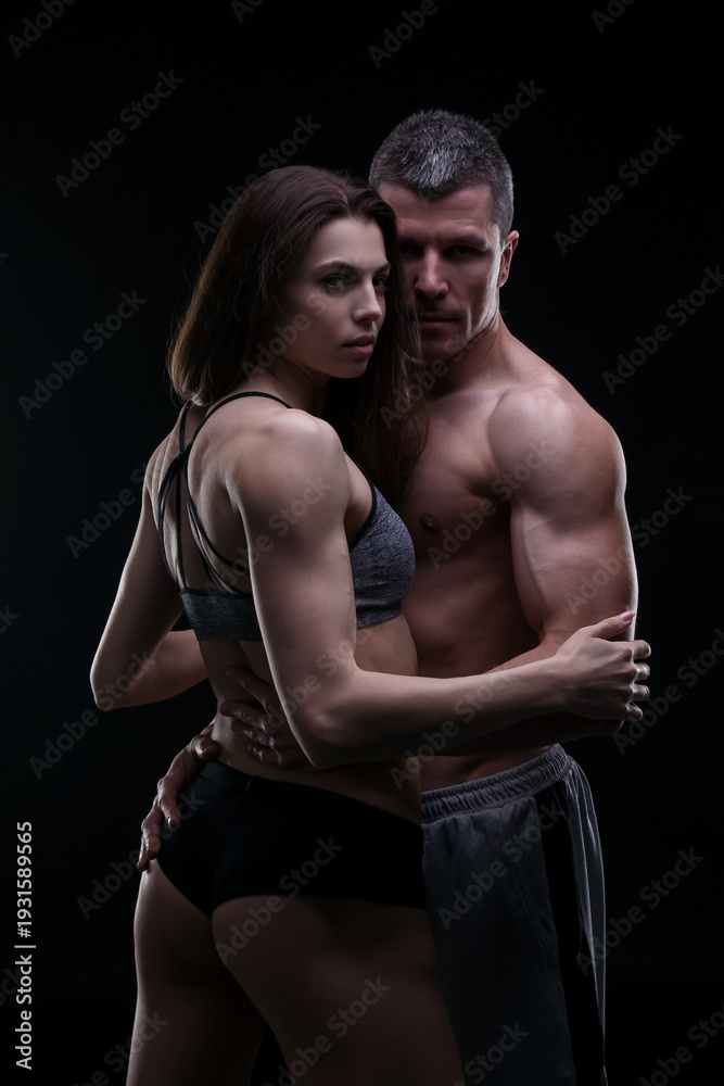 Obraz premium Sexy athletic couple portrait on black background, muscular man and fit woman posing together
