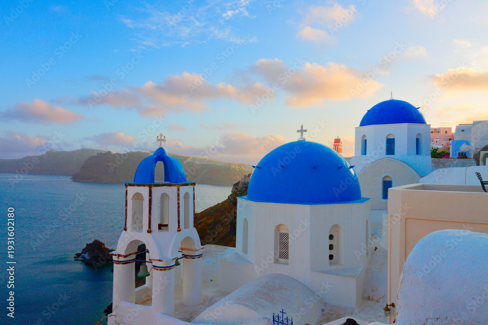 Obraz premium traditional white greek village Oia of Santorini, with blue domes of churches in sunset light, Greece