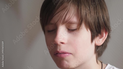Teenage boy making a funny face reacting to spicy food or strong taste. Emotional reaction of a child eating wasabi or ginger during sushi dinner.