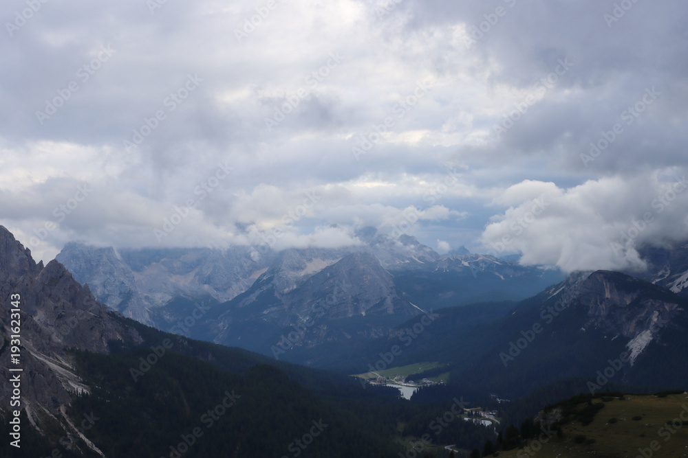 Fototapeta premium Dolomite ridges captured with heavy clouds above peaks along alpine hiking path