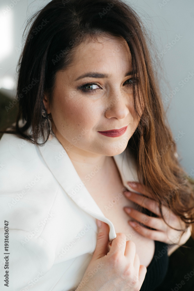 Naklejka premium Beautiful green-eyed brunette posing smiling. The woman is dressed in an office style. Portrait of a Happy Woman. A beautiful woman in white looks thoughtfully into the distance. 
