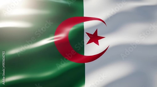The national flag of Algeria waving gracefully with its green and white halves, featuring a prominent red crescent and star, under bright illumination.