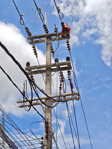 Low angle view of high voltage twisted aerial bundled cable termination on concrete utility pole with insulators against sky. Overhead power distribution grid infrastructure concept.