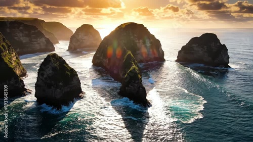 Coastal rock formations emerge from the ocean waves as sunlight casts dramatic shadows and highlights on the water's surface during a vibrant sunset