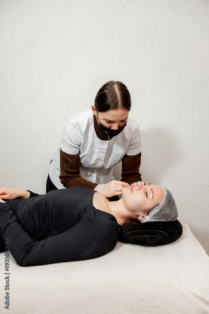 Obraz premium For a young client a cosmetologist in the salon performs mesotherapy with a syringe in the face area
