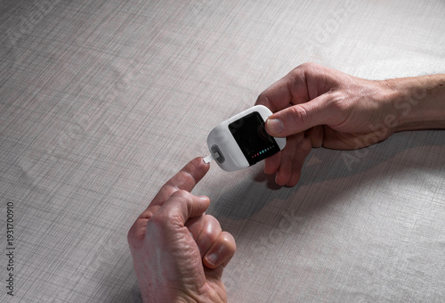 Close up of a man hands using a digital glucose meter to check blood sugar levels at home. Concept of diabetes management, medical self-testing, and healthcare monitoring for a healthy lifestyle.