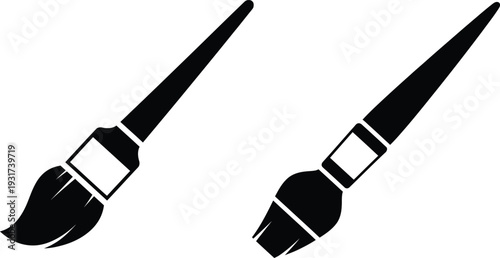Two black paintbrushes with white accents on a plain background