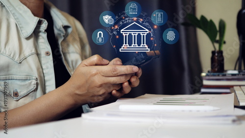 Business user holding smartphone with digital banking security icons, online payment system, biometric authentication, data protection and global fintech network technology concept.