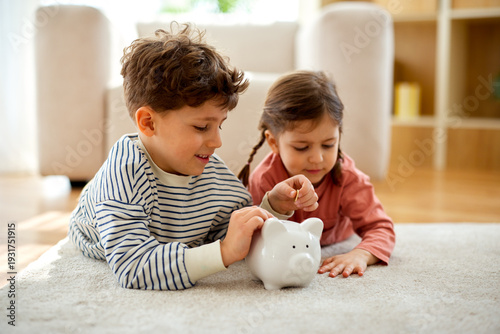 Foto Children putting coins into piggy bank at home