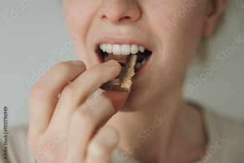 Close up of woman biting chocolate bar, sweet craving and sugar addiction concept