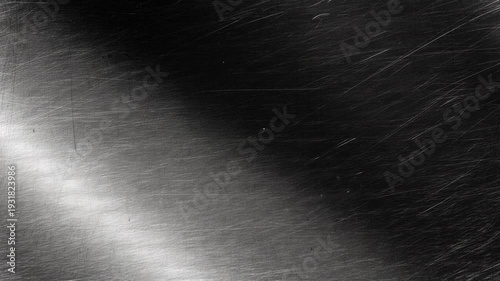 Dark brushed metal texture with visible scratches and a diagonal light reflection suitable for industrial backgrounds