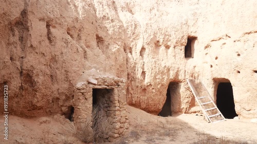 Panorama: Traditional troglodyte houses carved into rock in Matmata, Tunisia. Ancient underground dwellings in arid desert landscape, historic Berber architecture and cultural heritage site