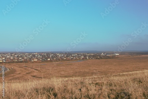 A large field with a road and buildings in the distance