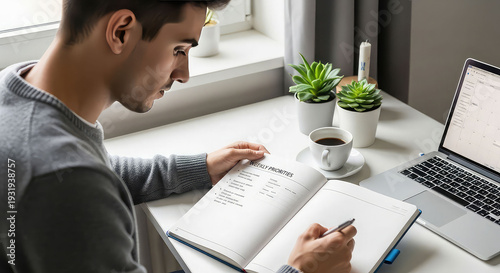 Man studying and writing in notebook at desk with laptop and coffee